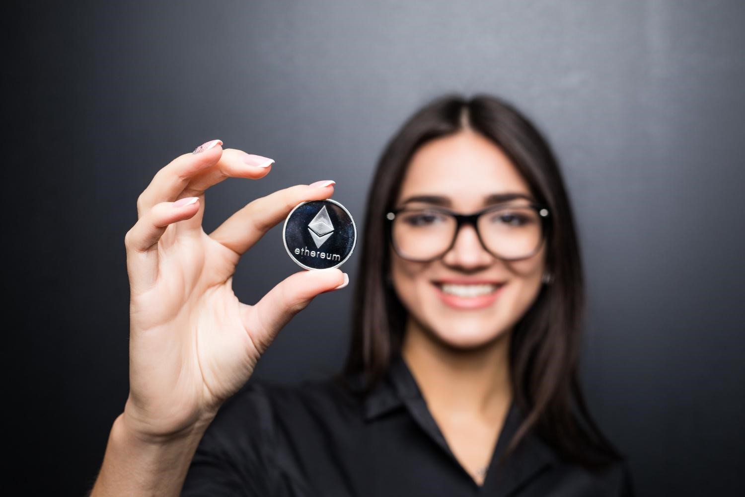 A woman holding a crypto coin (Image by diana.grytsku on Freepik)