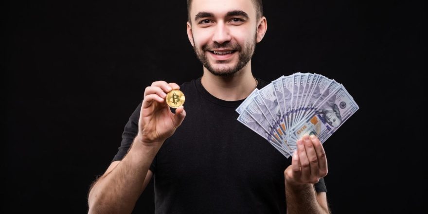 A man holding a crypto coin and bills (Image by diana.grytsku on Freepik)